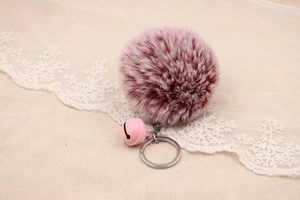 Detailed macro view of a pink and purple faux fur pompom keychain with a cute matching bell
