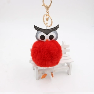 Détail du porte-clés pompon hibou rouge avec fermoir doré et texture en fausse fourrure