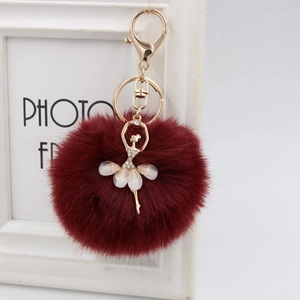 Detailed view of burgundy faux fur pompom keychain with gold ballerina dancer pendant