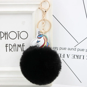 Detail of colorful unicorn charm with large black faux fur pom pom and gold keychain