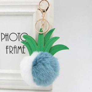 Detailed view of bicolor pineapple fur keychain with green faux leather leaves and gold clasp