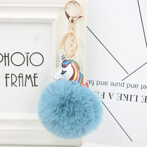 Detailed close-up of rainbow unicorn pendant with blue faux fur pom-pom and gold metal clasp