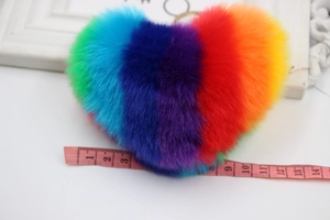 Rainbow heart pompom keychain with golden ring showing 9cm width on measuring tape