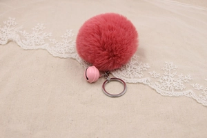 Close-up of fluffy pink faux fur pompom keychain with matching bell and silver metal ring