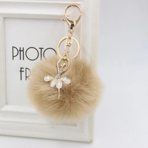 Detail of fluffy faux fur pompom with golden ballerina charm and sparkling rhinestones