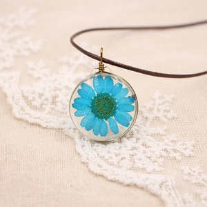 Détail macro du pendentif de marguerites séchées bleu ciel avec fermoir en bronze rétro