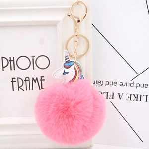 Close-up of fluffy pink pompom keychain with gold hardware and unicorn charm
