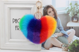 Close-up of fluffy rainbow heart keychain with golden metal clasp and soft plush texture