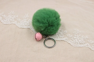 Detailed view of fluffy green faux fur pompom keychain with small pink metal bell