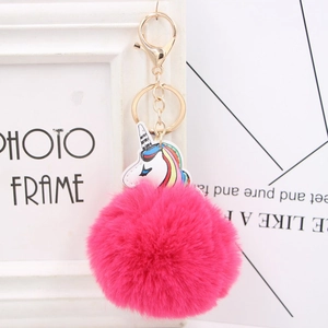 Close-up of fluffy pink pom-pom with rainbow unicorn charm and golden lobster clasp