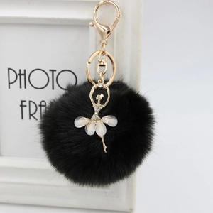 Close-up of fluffy black faux fur ball keychain featuring a golden ballerina charm with pearls