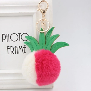 Detail of pineapple faux fur keychain with pink plush ball and green leather leaves