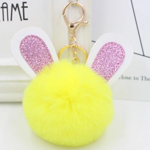 Detailed close-up of yellow pom-pom rabbit keychain with pink glitter ears and gold clasp