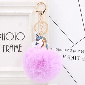 Detail of purple faux fur pompom keychain with unicorn charm and gold lobster clasp