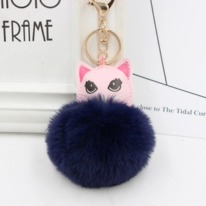 Détail du pendentif chat en cuir rose et du grand pompon bleu marine moelleux