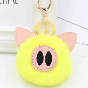 Close-up of bright yellow plush pig keychain with pink leather ears and gold metal clasp
