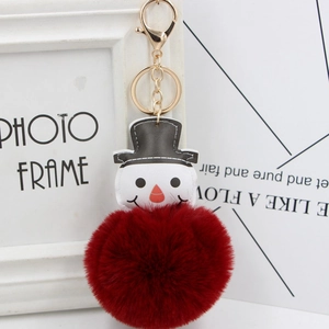 Gros plan du porte-clés bonhomme de neige avec pompon en fausse fourrure rouge et clip doré