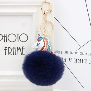 Close-up of fluffy dark blue pompom and rainbow PU leather unicorn keychain with gold clasp