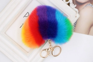 Close-up of rainbow faux fur heart keychain with gold clasp on white frame background