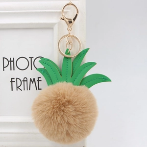 Detail of pineapple faux fur pom-pom keychain with green PU leaves and gold lobster clasp