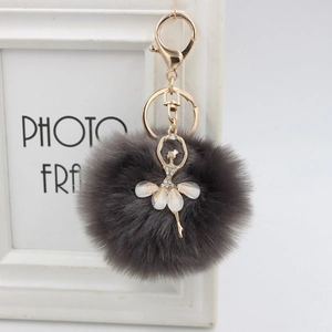 Detail of dark grey plush keychain with golden ballerina charm and crystal rhinestones