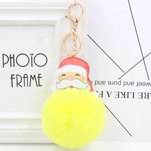 Close-up of bright yellow fluffy faux fur ball keychain with Santa Claus leather patch