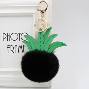 Close-up of faux fur pineapple keychain with green PU leaves and gold metal hardware