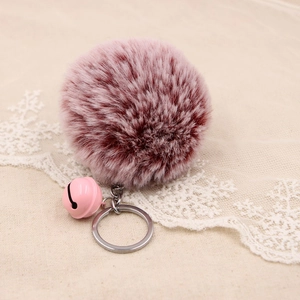 Detail of soft faux fur pompom keychain with matching pink bell and metal ring
