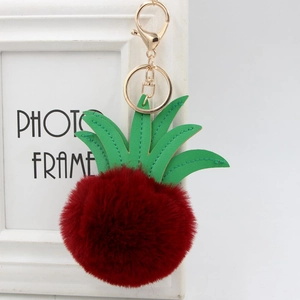 Detail of red faux fur pineapple keychain with green PU leaves and golden lobster clasp