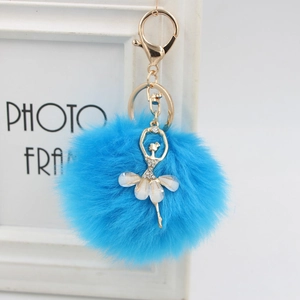 Detail of bright blue faux fur pompom keychain with gold ballerina dancer charm
