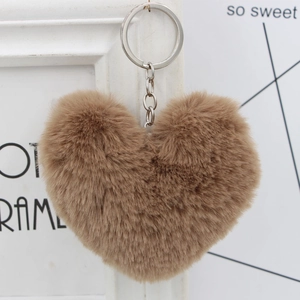 Close-up of a khaki faux fur heart keychain hanging on a minimalist white frame