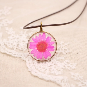 Gros plan d'une marguerite séchée dans un pendentif en résine avec cadre en bronze