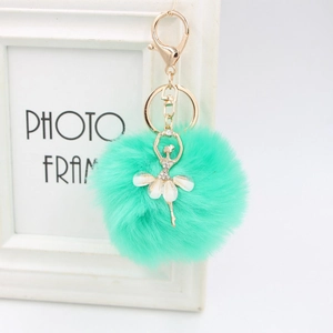 Detail of mint green faux fur pompom keychain with rhinestone ballet dancer charm