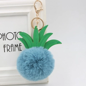 Close-up of blue pom-pom pineapple keychain with green PU leather leaves and gold clasp
