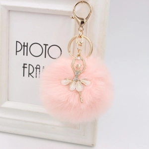 Close-up of fluffy pink faux fur pompom and golden ballerina keychain charm with rhinestones