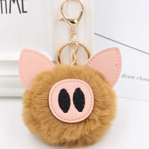 Detail of a brown plush pig keychain with pink leather ears and golden lobster clasp