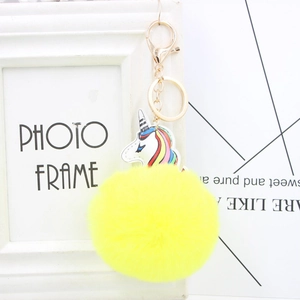 Detail of white unicorn charm with yellow faux fur pompom and golden keyring