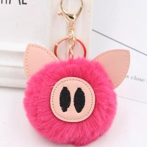 Close-up of fluffy rose pink pig plush keychain with leather ears and gold metal clasp
