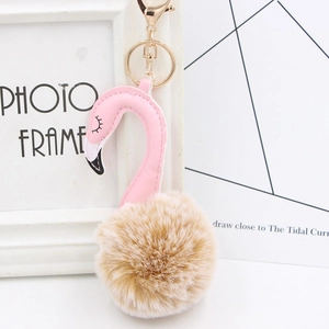 Detail of plush flamingo keychain with brown faux fur ball and golden metal clasp