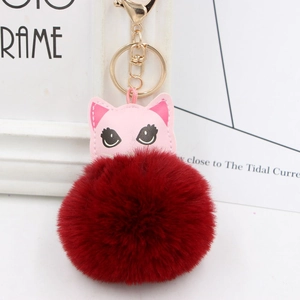 Détail du porte-clés pompon en fausse fourrure bordeaux avec un patch chat en cuir rose