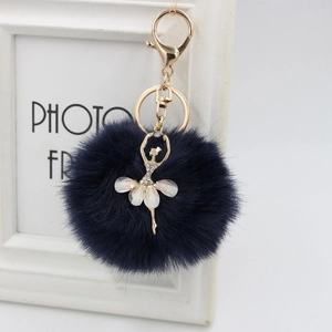 Detail of plush dark blue fur ball keychain with golden rhinestone ballerina pendant