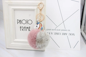 Detail showing the pink and gray fur ball unicorn keychain with golden lobster clasp