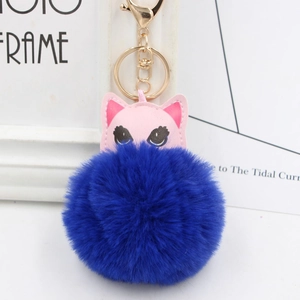 Détail d'un porte-clés chat en cuir rose avec pompon bleu foncé et fermoir doré chic