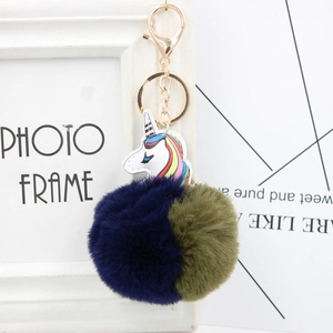 Detailed close-up of colorful unicorn faux fur pompom keychain with gold metal clasp