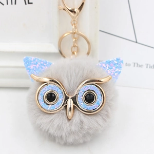 Detail showing grey faux fur owl keychain with sparkly blue sequins and golden metal clip