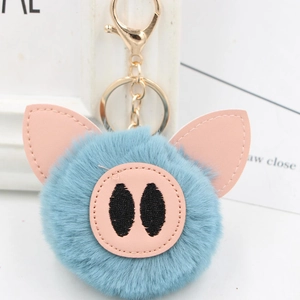 Close-up of fluffy blue plush pig keychain with pink PU leather nose and golden metal clasp