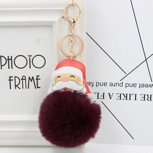 Detail of Santa Claus keychain with deep red faux fur pompom and golden metal clasp