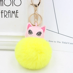 Détail d'un porte-clés chat en cuir rose avec un gros pompon jaune en fourrure synthétique