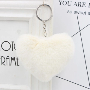 Close-up of white plush heart keychain with soft faux fur texture and silver metal ring