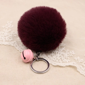 Detail of fluffy burgundy faux fur pompom keychain with pink bell and silver ring